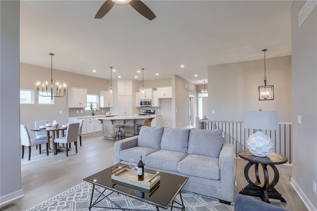 living room with sink, light wood-type flooring, and ceiling fan