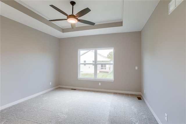 carpeted empty room with ceiling fan and a raised ceiling