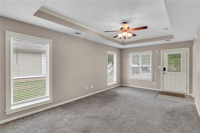 spare room with a wealth of natural light, a raised ceiling, light colored carpet, and ceiling fan