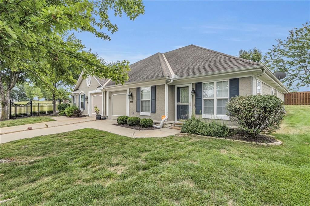 view of front of property featuring driveway, fence, roof with shingles, a front yard, and an attached garage