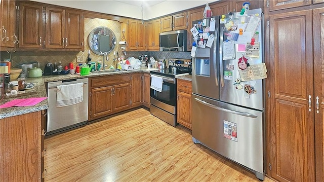 kitchen with sink, backsplash, light wood-type flooring, and stainless steel appliances