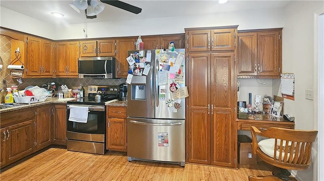 kitchen featuring ceiling fan, stainless steel appliances, decorative backsplash, light stone counters, and light hardwood / wood-style floors