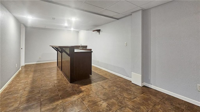 bar featuring dark tile patterned floors, dark brown cabinets, and a paneled ceiling