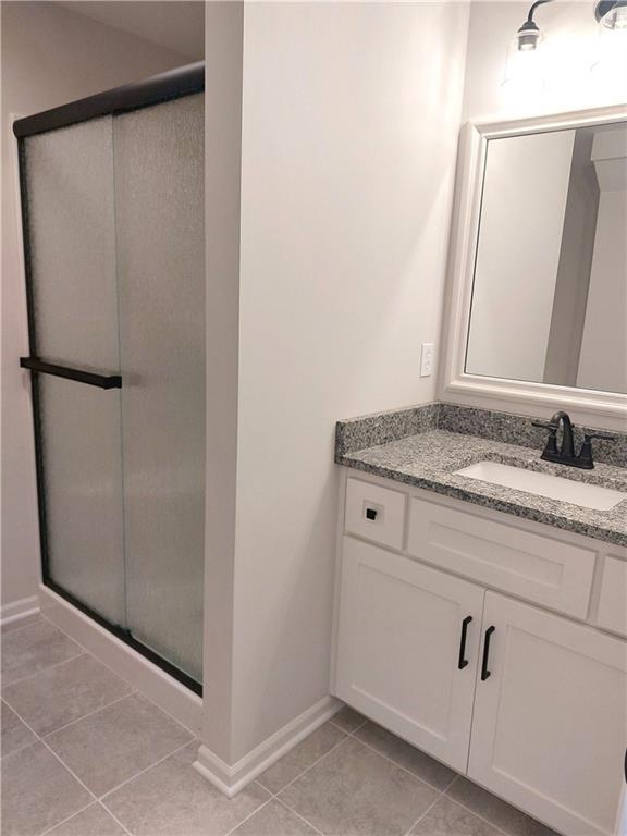 bathroom with vanity, walk in shower, and tile patterned flooring