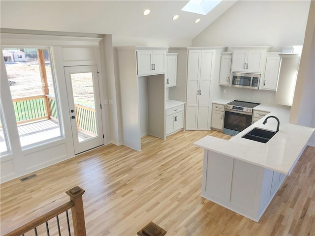 kitchen featuring stainless steel appliances, sink, light wood-type flooring, white cabinets, and light stone counters