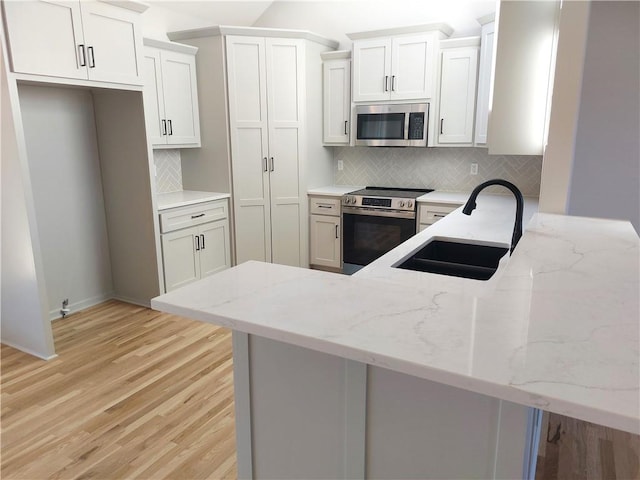 kitchen featuring white cabinetry, backsplash, appliances with stainless steel finishes, and sink