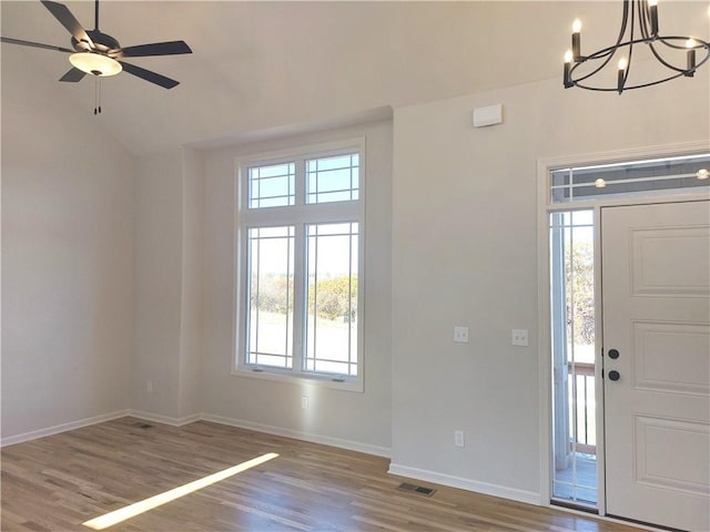 entrance foyer featuring lofted ceiling, light hardwood / wood-style flooring, and ceiling fan with notable chandelier