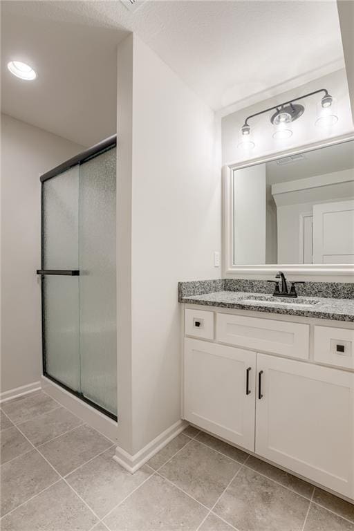 bathroom with vanity, a shower with shower door, and tile patterned floors