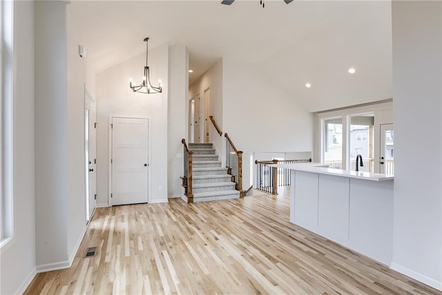 entrance foyer featuring an inviting chandelier, high vaulted ceiling, and light wood-type flooring