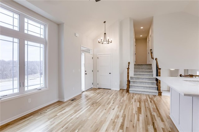 entryway featuring high vaulted ceiling, a notable chandelier, and light hardwood / wood-style floors