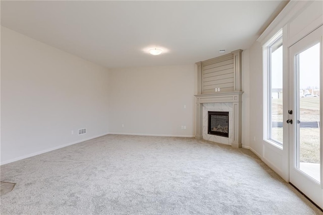 unfurnished living room featuring a tiled fireplace and light carpet