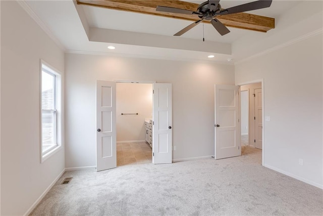 unfurnished bedroom featuring ensuite bathroom, light colored carpet, crown molding, and a tray ceiling