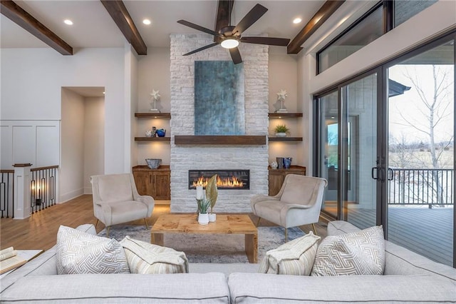 living room featuring a healthy amount of sunlight, a fireplace, beam ceiling, and light wood-type flooring