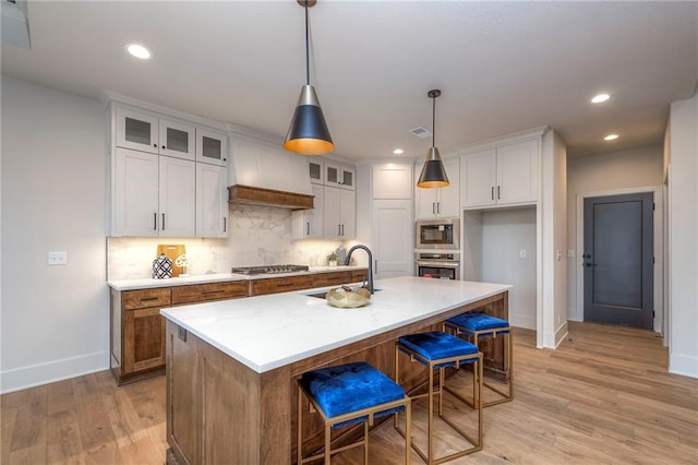 kitchen with white cabinetry, appliances with stainless steel finishes, a kitchen island with sink, and sink