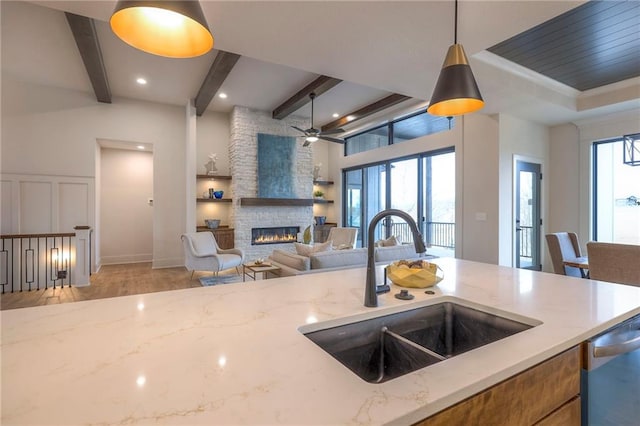 kitchen featuring pendant lighting, light stone countertops, sink, and dishwasher