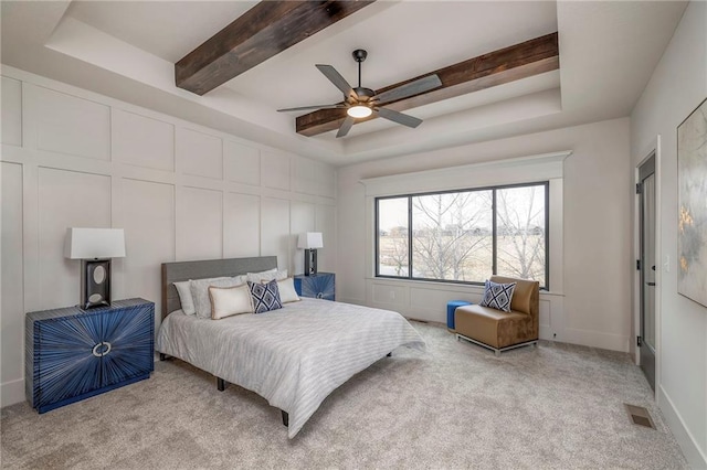 carpeted bedroom featuring ceiling fan, a raised ceiling, and beamed ceiling