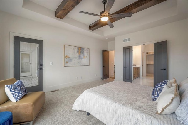 bedroom with connected bathroom, beamed ceiling, light colored carpet, ceiling fan, and a raised ceiling