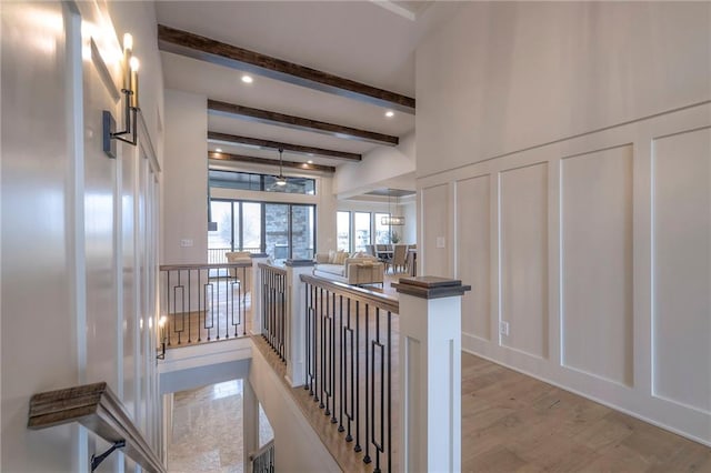 hall featuring beam ceiling and light hardwood / wood-style floors