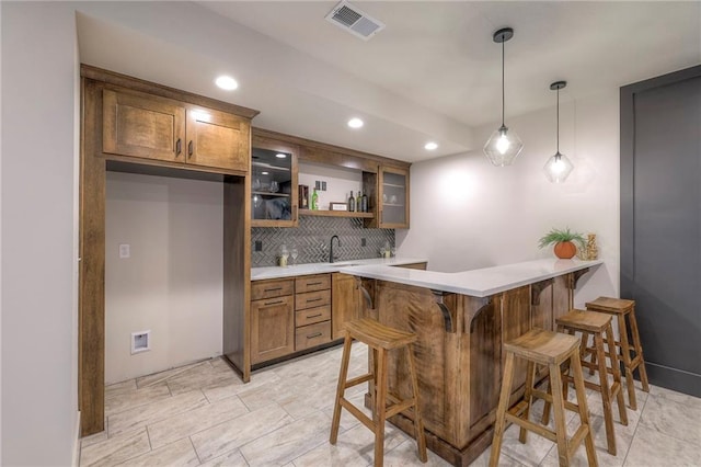 kitchen with decorative light fixtures, tasteful backsplash, sink, a kitchen breakfast bar, and kitchen peninsula