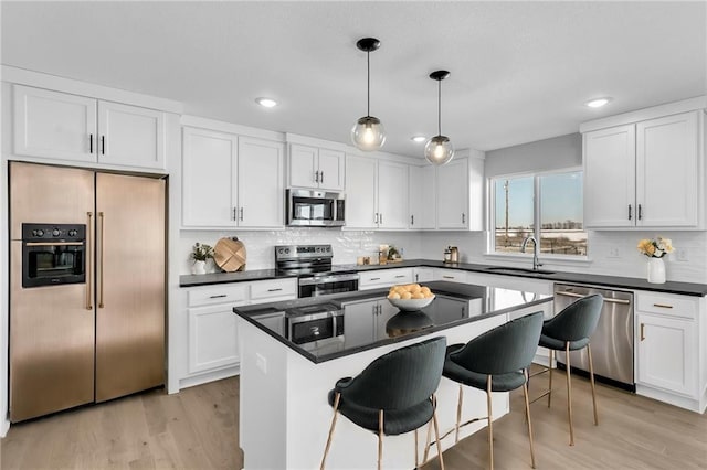 kitchen featuring decorative light fixtures, a kitchen island, white cabinets, and appliances with stainless steel finishes