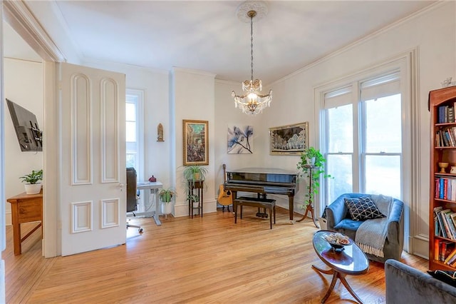 living area featuring crown molding, an inviting chandelier, light wood-style flooring, and a healthy amount of sunlight