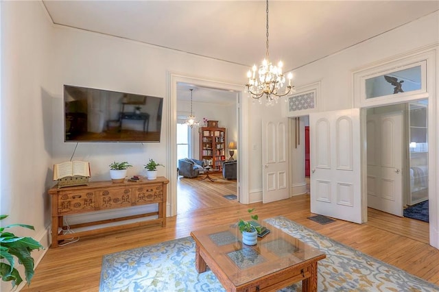 living room featuring baseboards, light wood-style flooring, and a notable chandelier