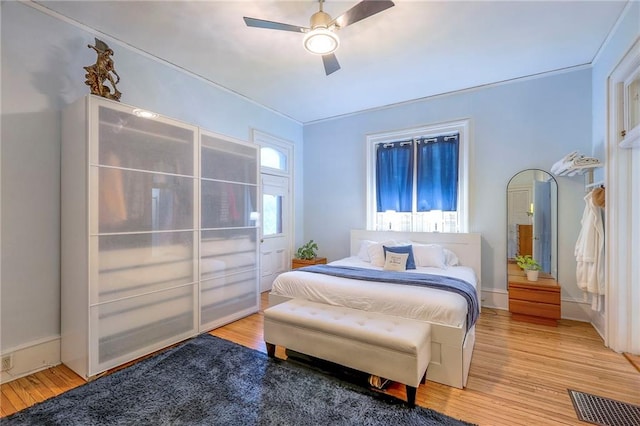 bedroom featuring light wood finished floors, visible vents, and ceiling fan