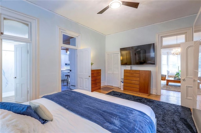 bedroom featuring ceiling fan with notable chandelier, baseboards, and wood finished floors