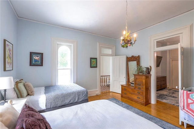 bedroom featuring an inviting chandelier, ornamental molding, and wood finished floors