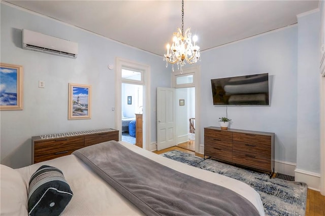 bedroom featuring an inviting chandelier, a wall mounted air conditioner, and wood finished floors