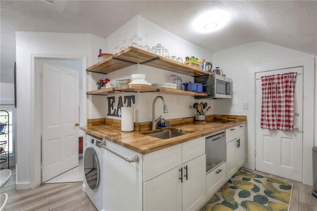 kitchen featuring wooden counters, washer / clothes dryer, stainless steel appliances, a sink, and open shelves