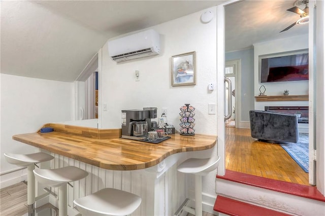 bar with a wall mounted air conditioner, baseboards, wood finished floors, a ceiling fan, and lofted ceiling