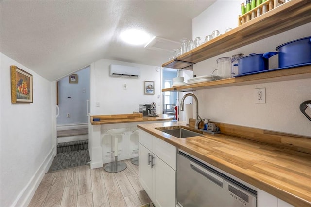 kitchen featuring a wall mounted air conditioner, dishwasher, wooden counters, a sink, and open shelves