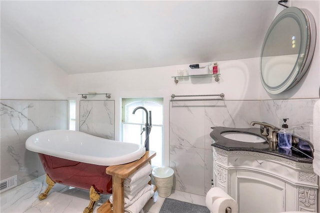 full bath with vanity, tile walls, marble finish floor, visible vents, and a freestanding bath