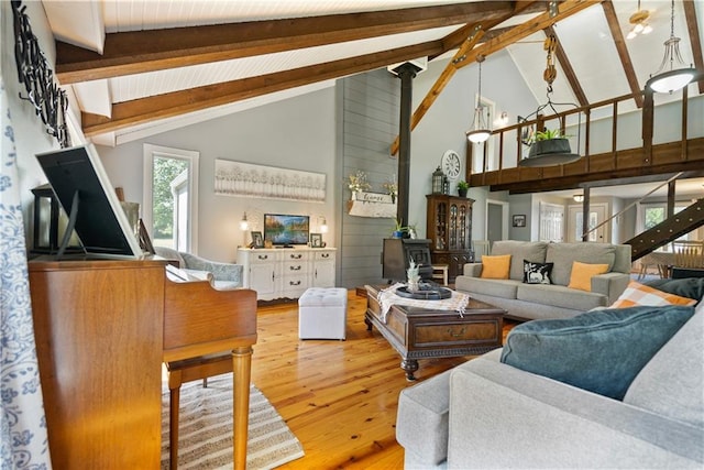 living room featuring hardwood / wood-style flooring, a wood stove, high vaulted ceiling, and beamed ceiling