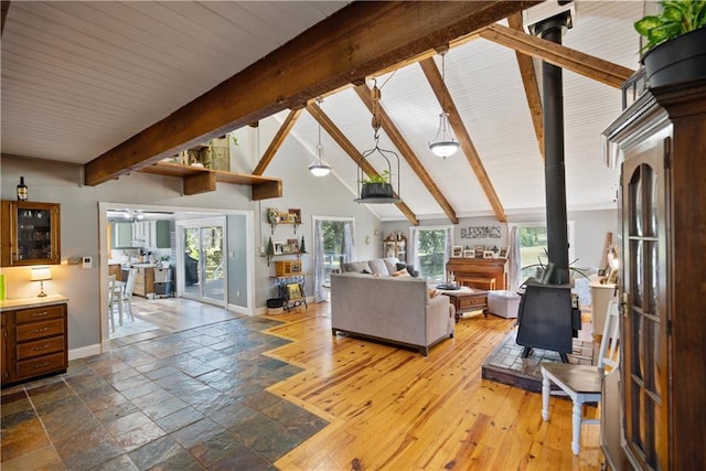 living room featuring hardwood / wood-style flooring, high vaulted ceiling, beamed ceiling, and a wood stove