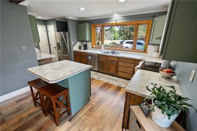 kitchen featuring a kitchen island, appliances with stainless steel finishes, a breakfast bar, sink, and hardwood / wood-style flooring