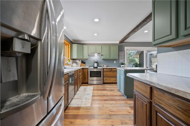 kitchen featuring sink, light hardwood / wood-style flooring, green cabinets, appliances with stainless steel finishes, and tasteful backsplash