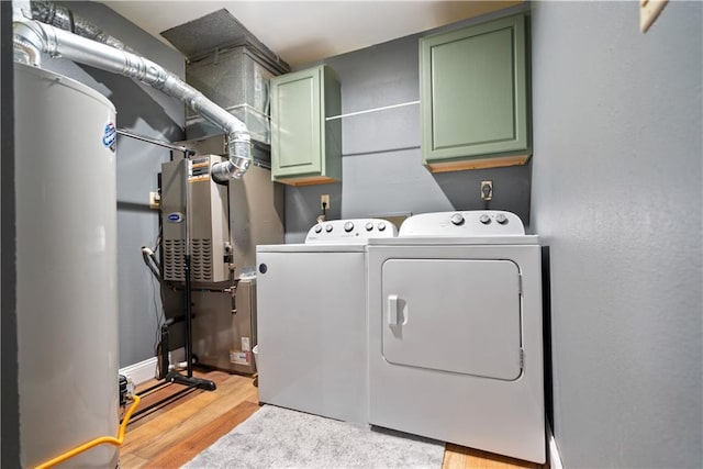 laundry area with separate washer and dryer, light hardwood / wood-style floors, and cabinets