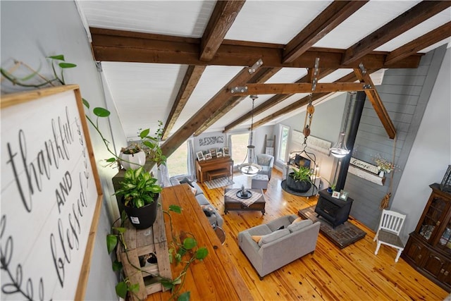 living room with wood-type flooring, lofted ceiling with beams, and a wood stove