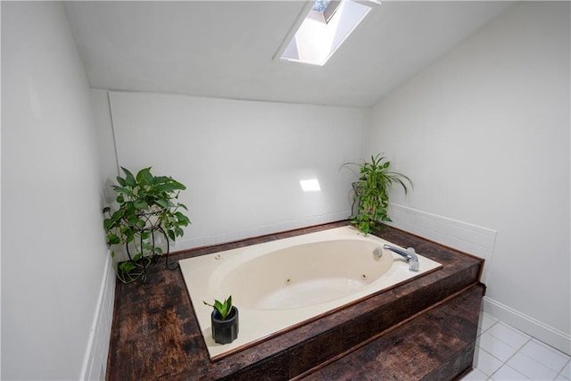 bathroom with tiled tub, lofted ceiling with skylight, and tile patterned floors