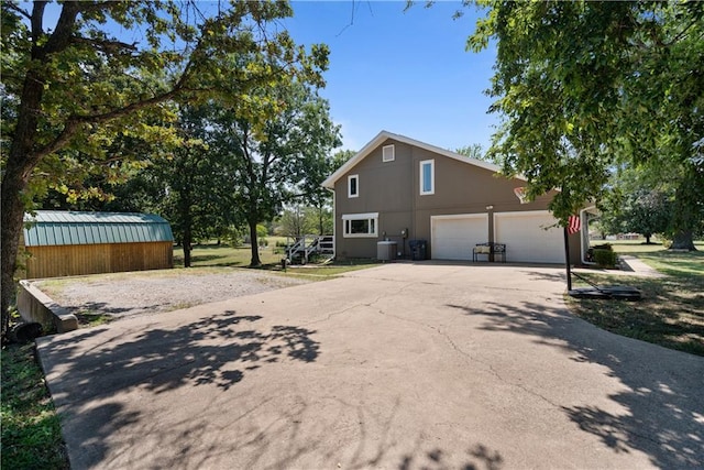 view of home's exterior with a garage, central AC unit, and a storage unit