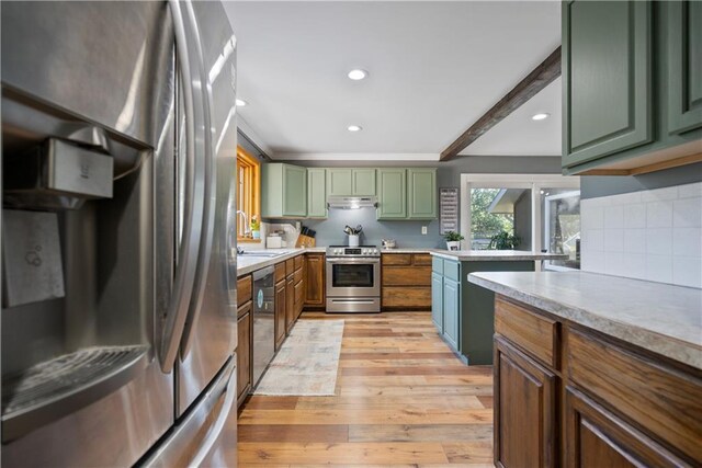 2924 Crown Dr, Independence, KS 67301 - kitchen featuring stainless steel appliances, green cabinetry, light wood-style flooring, light countertops, and tasteful backsplash