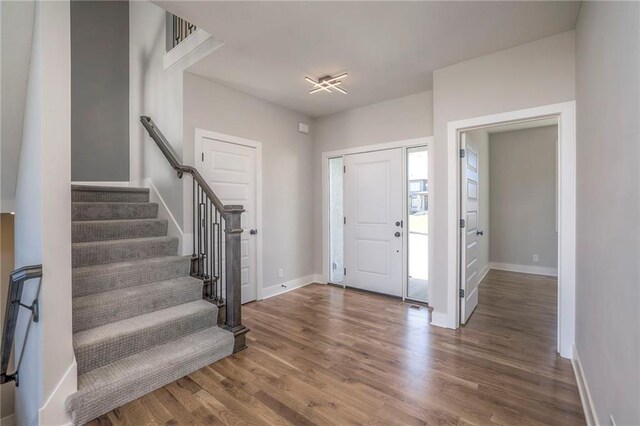 foyer featuring stairs, dark wood-style flooring, visible vents, and baseboards