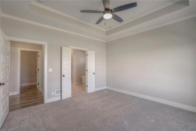 unfurnished bedroom with carpet, a raised ceiling, visible vents, and crown molding