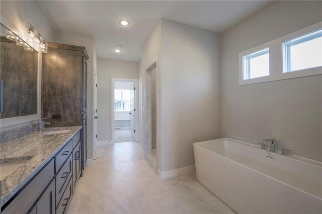 full bathroom with double vanity, a stall shower, baseboards, a soaking tub, and a sink