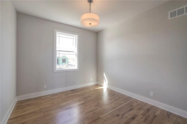 unfurnished room featuring baseboards, visible vents, and dark wood-style flooring