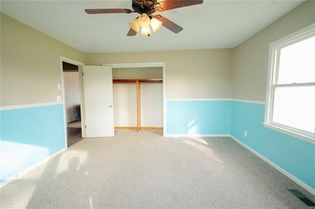 unfurnished bedroom with light carpet, a closet, multiple windows, and ceiling fan