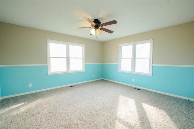 empty room with carpet flooring, ceiling fan, and a wealth of natural light