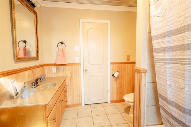 bathroom featuring toilet, vanity, tile patterned floors, and wood walls